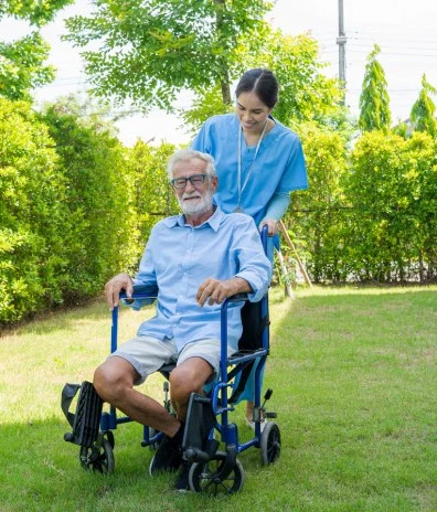 The image appears to depict a caring scene in which a healthcare worker is assisting an elderly man in a wheelchair.