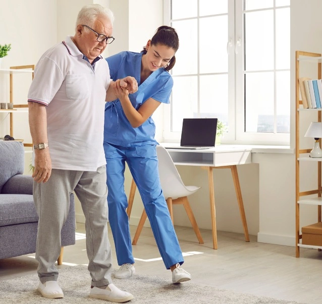 The image shows a caregiver assisting an elderly man who is walking.