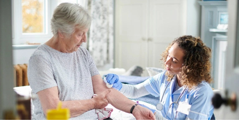 A caregiver is helping an elderly woman walk down the stairs, offering support with a smile, in a well-lit home environment