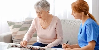 A healthcare worker and an elderly woman are engaged in a skill development activity, where the woman is using blocks to stimulate her cognitive abilities.