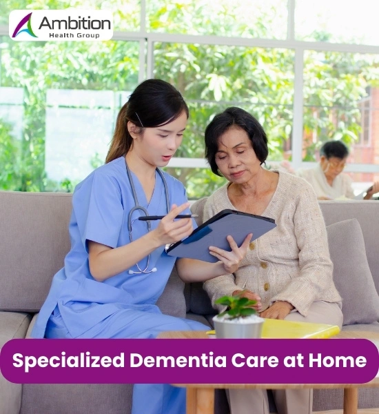 A young female healthcare professional in blue scrubs sitting on a couch and discussing medical information on a tablet with an elderly woman at home.